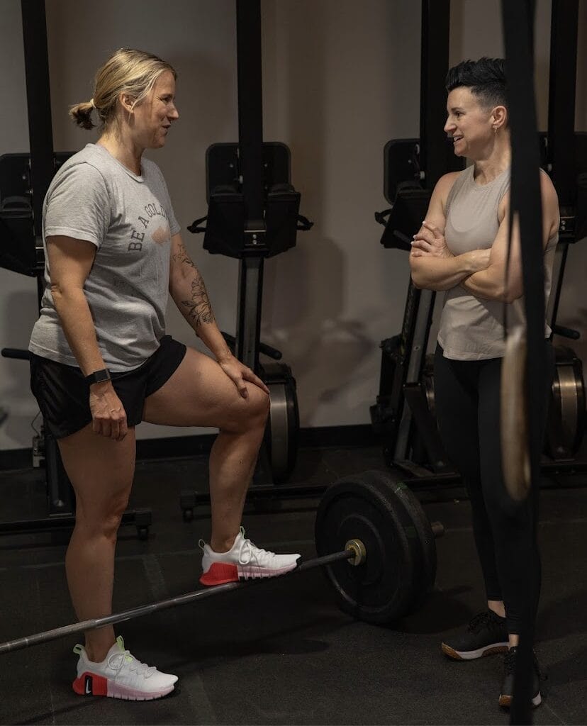 Coach teaching foundational strength training exercises and compound lifts to a woman in her 40s